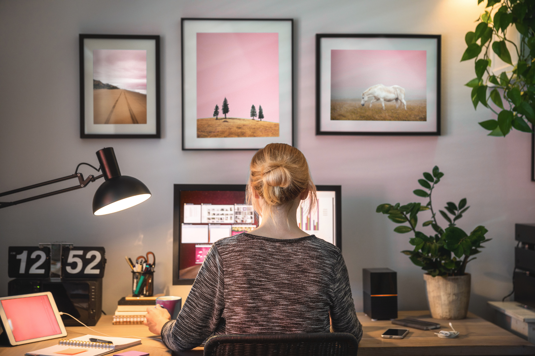 Woman working at a stylish home desk with pink artwork